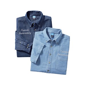 May include: Two denim shirts, one long-sleeved and one short-sleeved, in shades of blue. Both shirts have button-down collars, button closures, and a pocket. The text "Custom Embroidery" is embroidered on the front of each shirt.