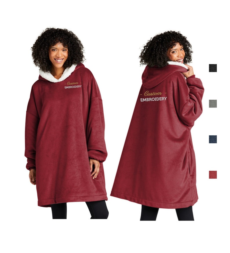 Pu&ograve; includere: Una felpa con cappuccio oversize bordeaux con cappuccio foderato in sherpa bianco. Il testo ricamato "Custom EMBROIDERY" &egrave; presente sulla parte anteriore e posteriore. L'immagine mostra la felpa con cappuccio da davanti e da dietro, con campioni di colore.