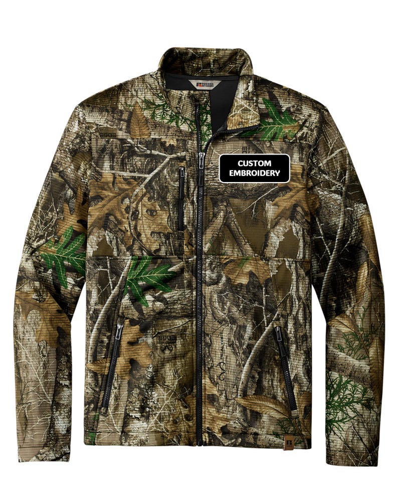 May include: A camouflage jacket with a full zipper, black accents, and the text "CUSTOM EMBROIDERY" on a black and white patch. The jacket features a high collar and multiple pockets, ideal for outdoor activities.