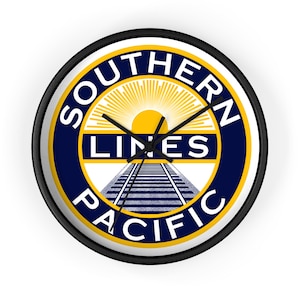 Puede incluir: Reloj de pared redondo con marco negro. La esfera muestra el logotipo de Southern Pacific Lines en azul marino, amarillo y blanco, con un diseño de vías de tren y la inscripción "Southern Pacific" en círculo.