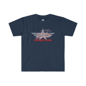 Puede incluir: Camiseta azul marino con un gráfico de un avión de combate dentro de una estrella y el texto "highway to the DANGER ZONE" en rojo y blanco. La camiseta tiene cuello redondo y mangas cortas.