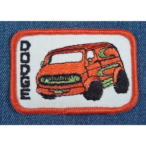 May include: An embroidered patch featuring a red Dodge van with green and orange details. The word "DODGE" is embroidered vertically on the left side of the patch.
