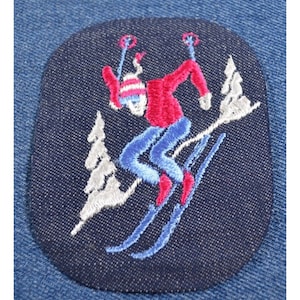 May include: Embroidered patch of a skier in blue and red clothing, skiing down a snowy slope with two trees in the background.