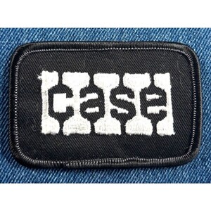 May include: Black embroidered patch with white lettering that reads "CASH" in a stylized font.