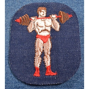Puede incluir: Parche bordado con una figura musculosa levantando una barra con pesas rojas y marrones. La figura lleva un calzoncillo rojo y botas rojas. El parche está sobre un fondo azul oscuro.