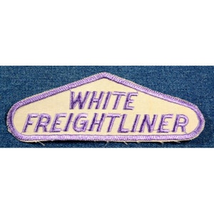 May include: A white and purple embroidered patch with the text "WHITE FREIGHTLINER" in a purple font.