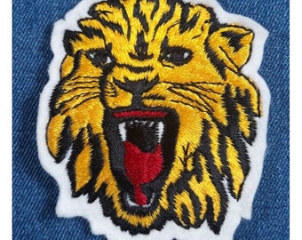 May include: Embroidered iron-on patch featuring a yellow and black tiger head with a red open mouth. The tiger is roaring with its teeth showing.