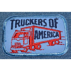 May include: A blue and red embroidered patch with the text "Truckers of America" and a red semi-truck illustration.
