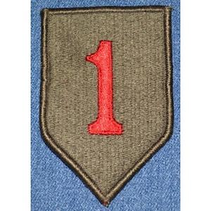 May include: Embroidered patch featuring a shield shape with a dark olive green background and a red number 1 in the center. The patch has a black border and is likely for military or historical purposes.