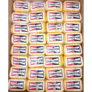 May include: A box filled with multiple rectangular patches. Each patch has a yellow border, a white center with the word "CHAMPION" in black, and a red and black design. The patches are ready to be sewn on.