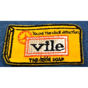May include: Yellow and black embroidered patch with the words "Vile, The Odor Soap" and a clock with the text "Round the clock detection".