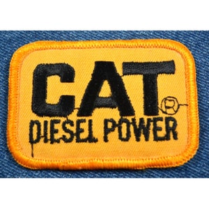 May include: A yellow embroidered patch with black stitching that reads "CAT DIESEL POWER".
