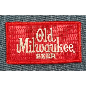 May include: Red embroidered patch with white text that reads "Old Milwaukee Beer".