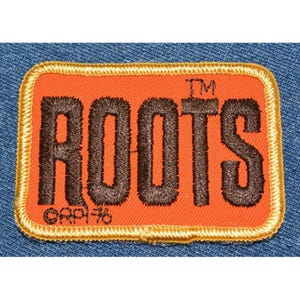 May include: Orange rectangular patch with the word "ROOTS" embroidered in dark brown. The patch has a gold border and the text "©RPI-76" is at the bottom. The patch is set against a blue denim background.