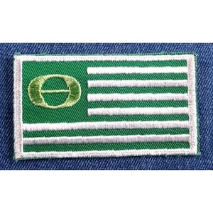May include: Green and white embroidered patch with a green circle containing a white letter "O" with a horizontal line through it.