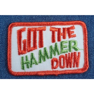 May include: A white embroidered patch with an orange border. The patch says "Got the Hammer Down" in red and green lettering.