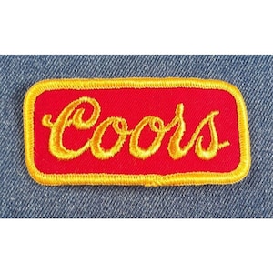 May include: A red and gold embroidered patch with the word "Coors" in a cursive font.