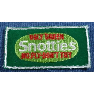 May include: A green embroidered patch with white stitching. The patch has a green oval with the text "Ugly Green Snotties" in white and "No Ply - Don't Try" in red.