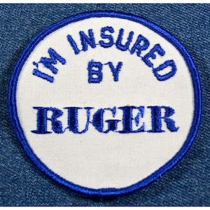 以下が含まれることがあります： 「I'm Insured By Ruger」と青い刺繍で書かれた白い丸いパッチ。