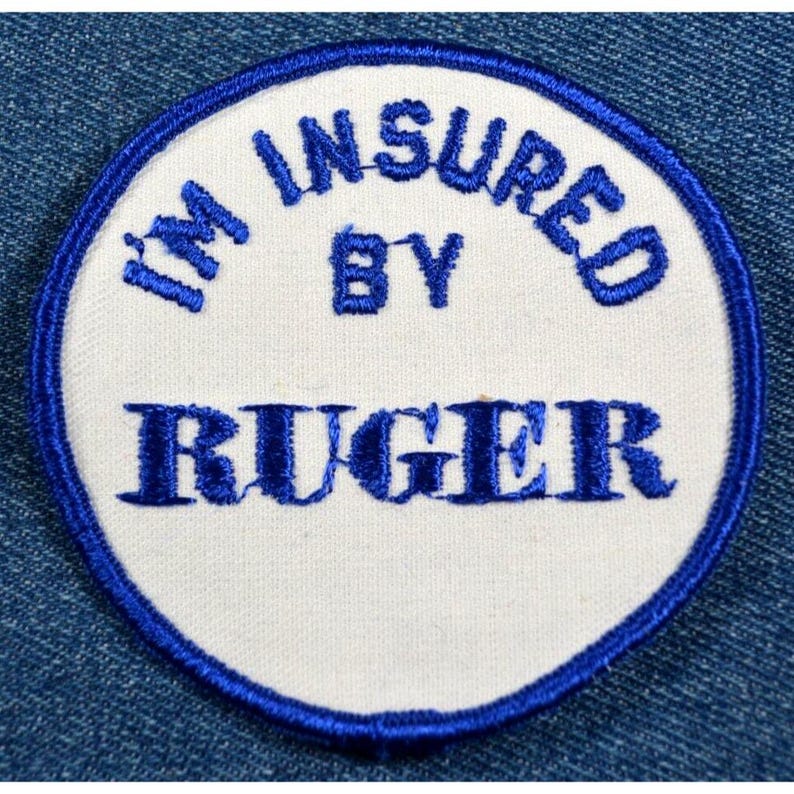 以下が含まれることがあります： 「I'm Insured By Ruger」と青い刺繍で書かれた白い丸いパッチ。