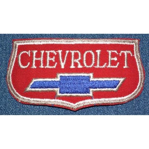 May include: Embroidered patch featuring the word "CHEVROLET" in white lettering above a blue bowtie logo. The patch has a red background with a silver border, and is set against a blue denim background.