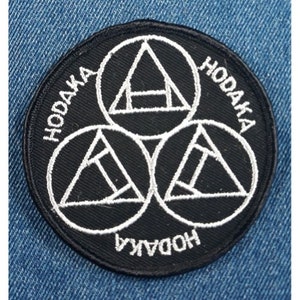 May include: Black and white embroidered patch with three interlocking circles containing triangles and the word "HODAKA" repeated around the edge.