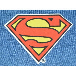 May include: Red and yellow Superman logo on a blue denim background.