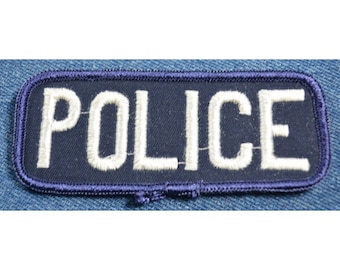 May include: A blue fabric patch with white embroidered lettering that reads "POLICE".