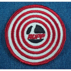 May include: A red and white circular patch with a black and white logo in the center. The logo says "Rupp" in white letters.