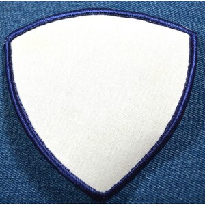 May include: A white triangle patch with a dark blue stitched border. The patch is made of fabric and is ready to be customized.