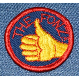 May include: A red, white, and blue embroidered patch with a thumbs up hand gesture and the text "The Fox" in a circle.