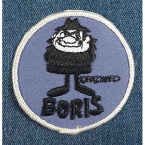 May include: Embroidered patch featuring a cartoon character named "Boris" in a black coat and hat, with a stern expression. The patch is circular, with a light blue background and white border, and is sewn onto denim.
