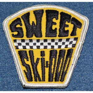 May include: Yellow and black embroidered patch with the text "SWEET SKIPOO" and a black and white checkered stripe.