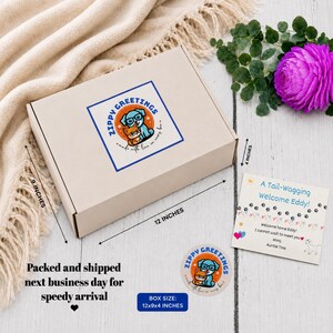 May include: A beige gift box with a Zippy Greetings sticker featuring a dog and cat. The box measures 12 x 9 x 4 inches. A card reads "A Tail-Wagging Welcome Eddy!" with a message from Auntie Tina. The box is on a white wooden surface.