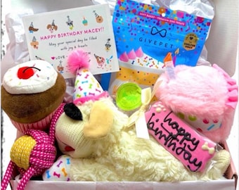 May include: A gift box filled with dog toys and treats. Includes a plush dog toy, a cupcake toy, a pink birthday hat, a bag of dog treats, and a card that says "Happy Birthday Macey!!". The box also contains a pink cookie that says "happy birthday".