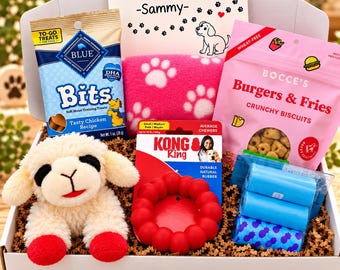 May include: A white gift box containing a plush cream-colored lamb toy with red feet, a bag of Blue Bits chicken treats, a bag of Bocce's Burgers & Fries biscuits, a red Kong Ring toy, a pink paw-print blanket, blue waste bags, and a card reading A Tail-Wagging Welcome!! -Sammy-.