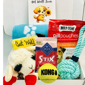 May include: A gift box filled with dog-themed items. Includes a plush lamb, a blue blanket with paw prints, dog treats, a tennis ball, and a rope toy. A card with a cartoon puppy and the words "Get Well Soon" is also included.