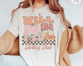 May include: White t-shirt with a retro design that says "Will Run For Pie" with a cute pie graphic and "Turkey Trot" underneath.