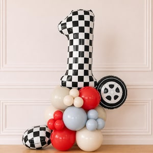 May include: A large number one foil balloon with a black and white checkered pattern, accompanied by a cluster of round latex balloons in red, light blue, cream, and white, plus a round foil balloon featuring a black and white tire design.