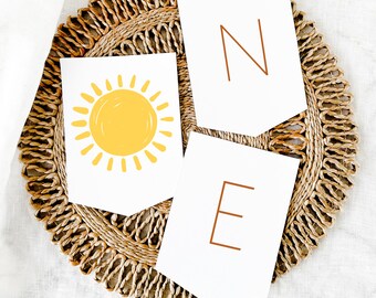 May include: White paper pennants with the word "ONE" in brown letters. The "O" is a yellow sun with orange rays.