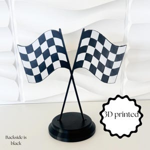 May include: A 3D printed decorative stand featuring two crossed checkered racing flags in black and white. The flags are mounted on a circular black base. The text 3D printed is visible on the right, and the text Backside is black is on the left.
