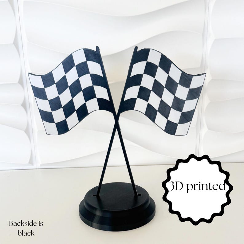 May include: A 3D printed decorative stand featuring two crossed checkered racing flags in black and white. The flags are mounted on a circular black base. The text 3D printed is visible on the right, and the text Backside is black is on the left.