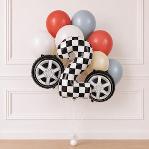 Puede incluir: Un ramo de globos que incluye un globo de aluminio grande con forma del número dos con un patrón de cuadros blancos y negros, dos globos de aluminio redondos con forma de neumáticos de coche y varios globos de látex redondos en rojo, blanco, gris y crema.