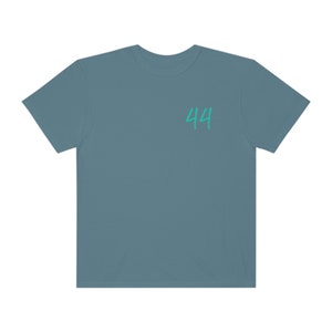 Peut inclure: Un t-shirt bleu sarcelle avec le num&eacute;ro 44 imprim&eacute; sur le devant en vert turquoise.