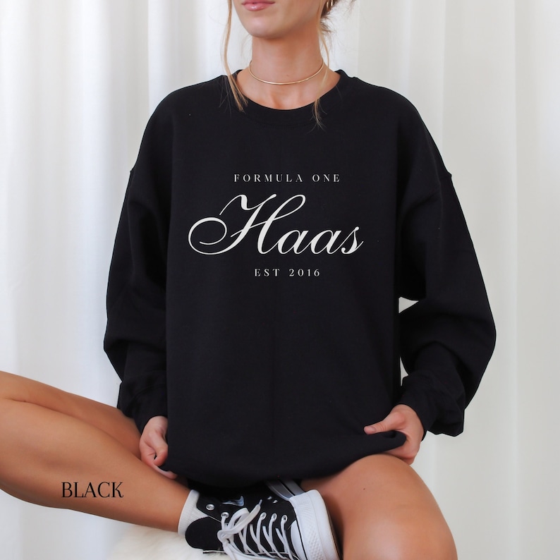 May include: Black sweatshirt with white text that reads "Formula One Haas Est 2016".
