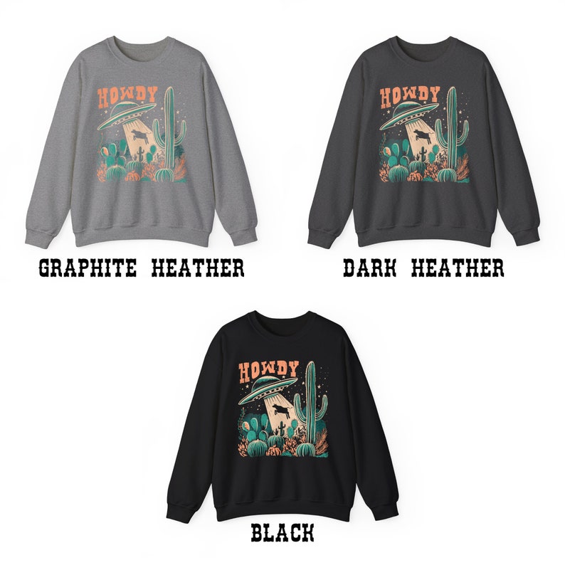 May include: A sweatshirt with a graphic print of a UFO over a desert landscape with the text "Howdy". The sweatshirt is available in three colors: graphite heather, dark heather, and black.