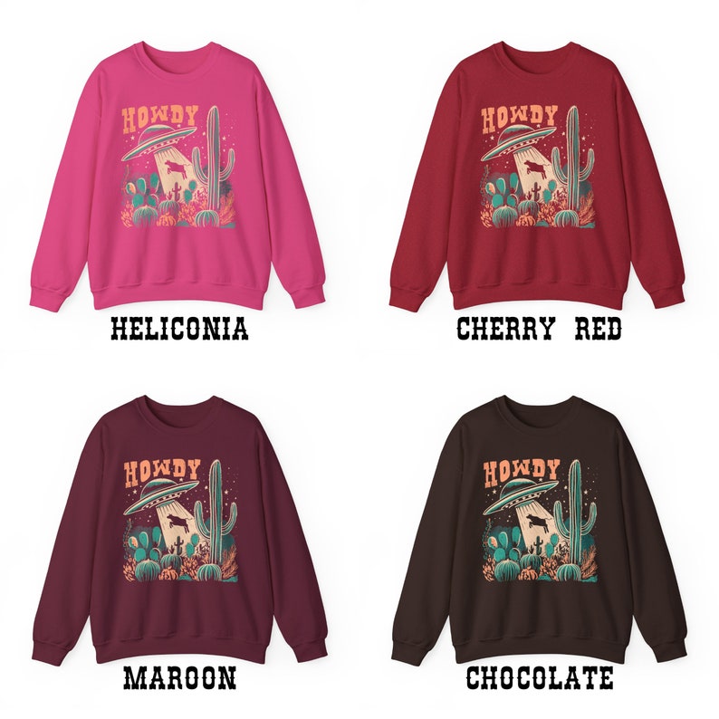 May include: Four different color sweatshirts with a graphic print of a UFO abducting a cow in a desert landscape with cacti. The text "Howdy" is printed above the UFO. The colors are Heliconia, Cherry Red, Maroon, and Chocolate.