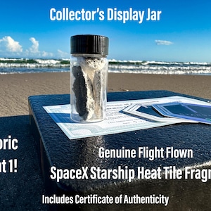 May include: A small glass jar with a black lid containing fragments of a SpaceX Starship heat tile. The jar is sitting on a black surface with a certificate of authenticity. The text on the certificate reads "Genuine Flight Flown SpaceX Starship Heat Tile Fragments".