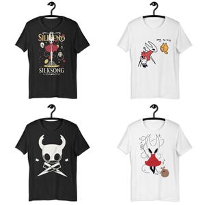 May include: Four short-sleeve t-shirts hanging on black hangers. Two are black and two are white. The shirts feature graphic prints of characters from the video game Hollow Knight, including Hornet and the Knight, with text reading SILKSONG.