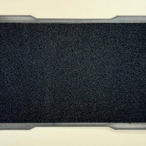 May include: Rectangular black hook and loop patch with a grey border. The border has a unique design with integrated attachment points. The patch is likely for attaching items to a surface.